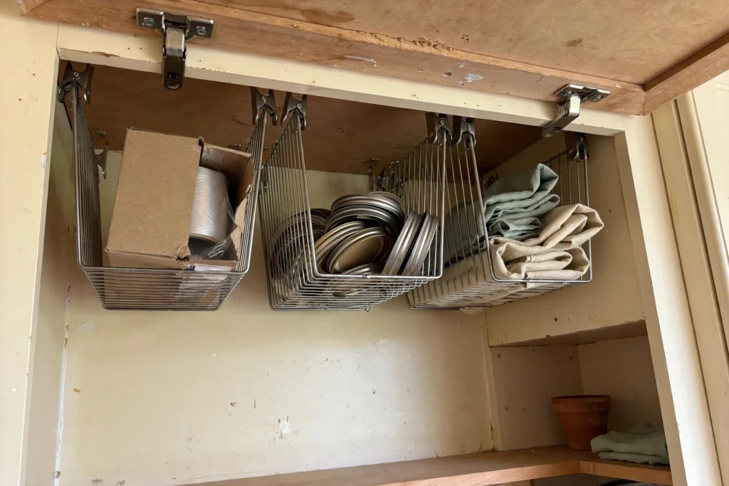 Clip-on under-shelf baskets hanging beneath a cabinet shelf